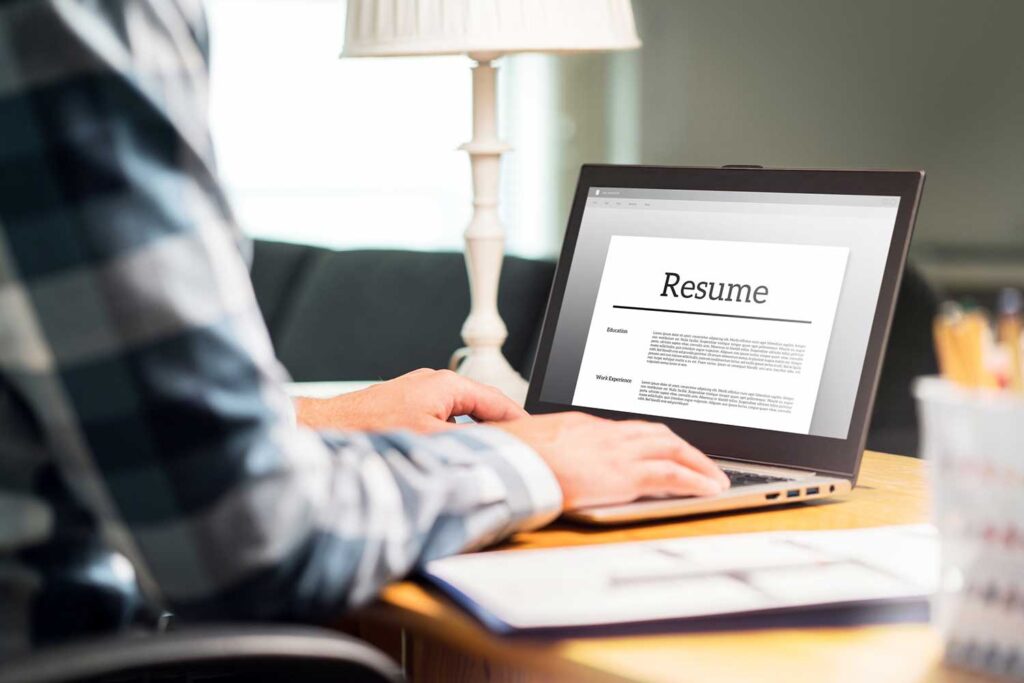 man writing resume on laptop